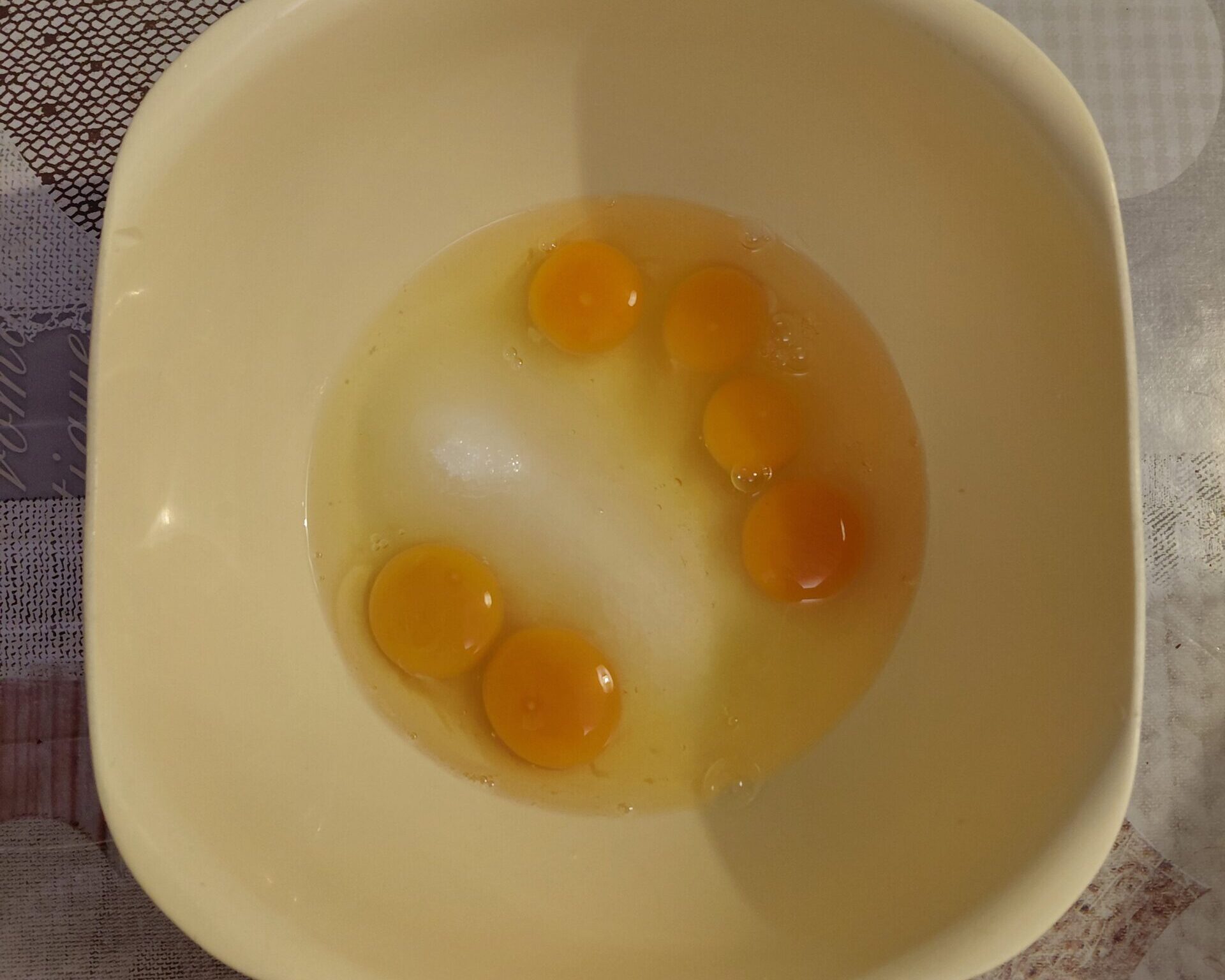 Uova aperte nella ciotola, tuorli e albumi insieme.